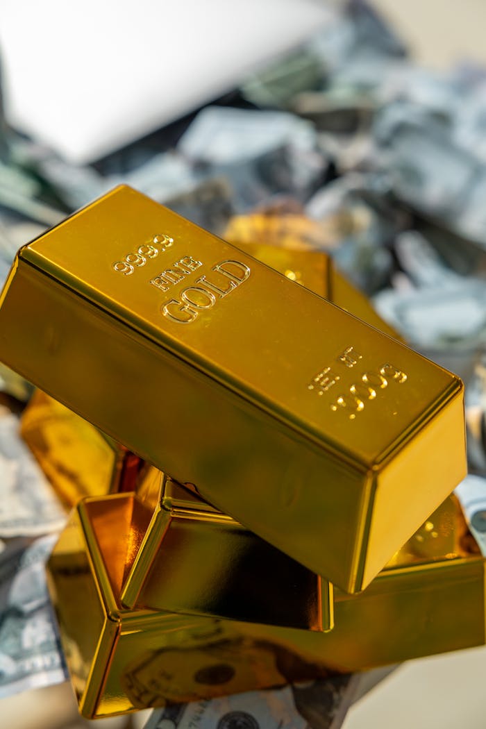 Close-up of shiny gold bars stacked on a pile of cash, representing wealth and investment.